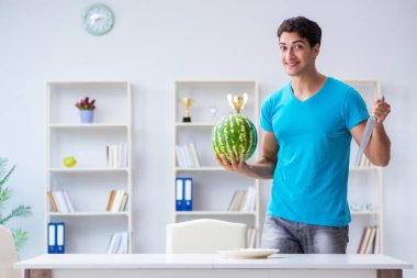 Evde karpuz yiyen bir adam.