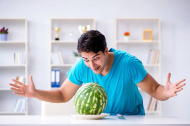 Evde karpuz yiyen bir adam.