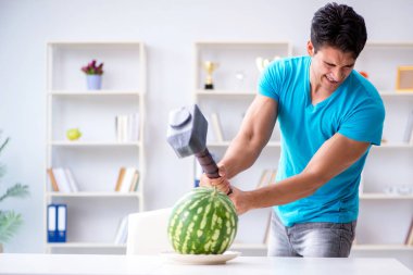 Evde karpuz yiyen bir adam.