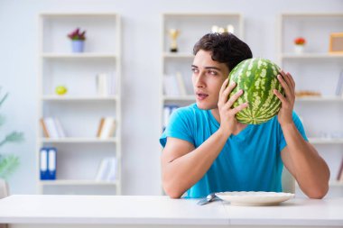 Evde karpuz yiyen bir adam.