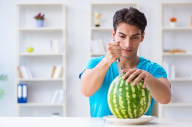 Evde karpuz yiyen bir adam.