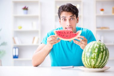 Evde karpuz yiyen bir adam.