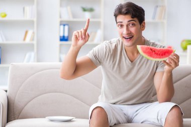 Evde karpuz yiyen bir adam.