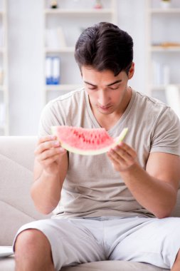 Evde karpuz yiyen bir adam.