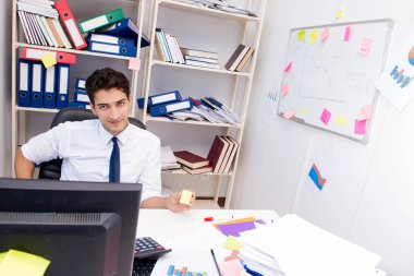 Ofiste kitap ve kağıtlarla çalışan bir işadamı.