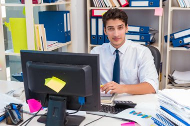 Ofiste kitap ve kağıtlarla çalışan bir işadamı.