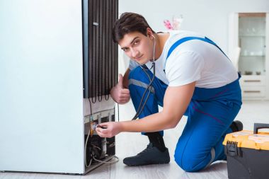 Tamirci müteahhit DIY konseptinde buzdolabını tamir ediyor.