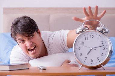 Yataktaki adam alarm yüzünden uykusuzluk çekiyor.