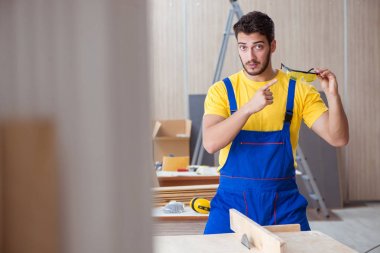 Genç tamirci marangoz odun kesiyor.