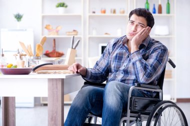 Engelli genç koca mutfakta çalışıyor.