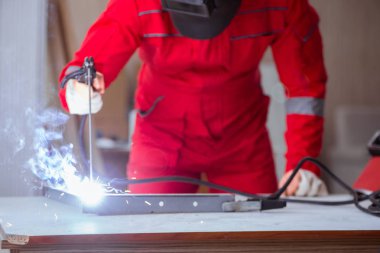 Kaynak tabancası elektrot ve kask takan genç bir tamirci.