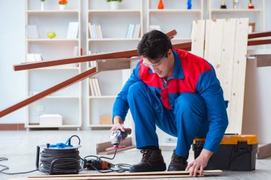 Genç marangoz ahşap kalaslarla çalışıyor.