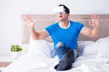 Yatakta sanal gerçeklik başlığı takan genç bir adam.