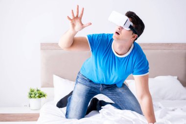 Yatakta sanal gerçeklik başlığı takan genç bir adam.