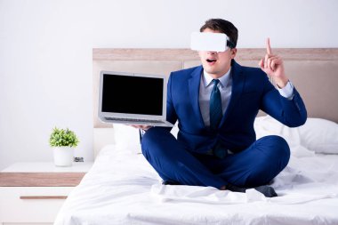 Yatak odasında sanal gerçeklik kulaklığı takan bir iş adamı.