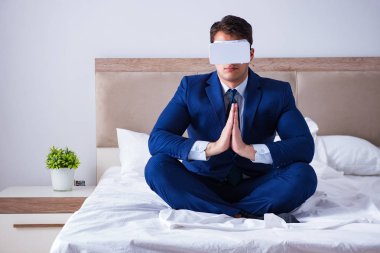 Yatak odasında sanal gerçeklik kulaklığı takan bir iş adamı.