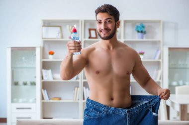 Kilo verme konseptinde büyük beden pantolon giyen bir adam.