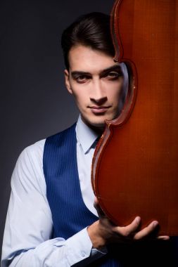 Genç adam karanlık odada çello çalıyor.