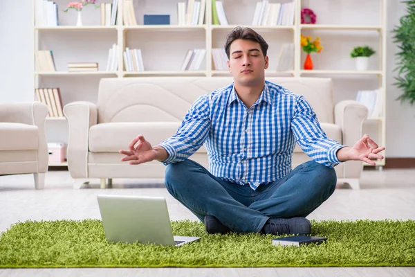 Genç yakışıklı adam evde yerde oturuyor.