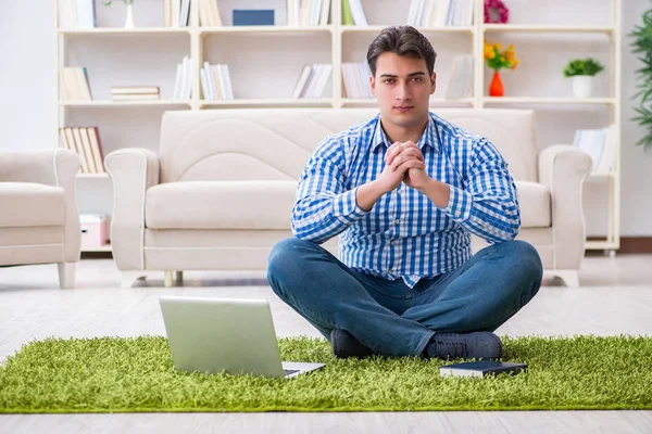 Genç yakışıklı adam evde yerde oturuyor.