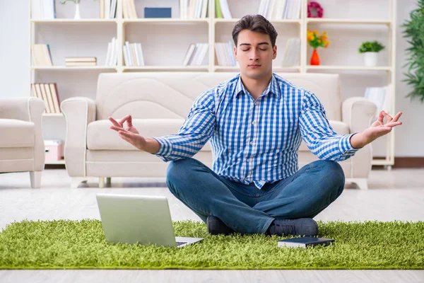 Genç yakışıklı adam evde yerde oturuyor.
