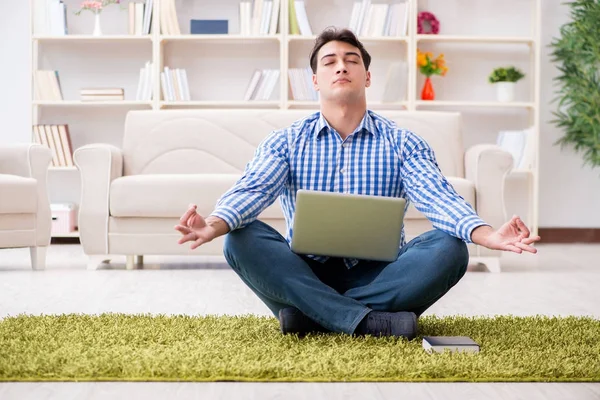 Genç yakışıklı adam evde yerde oturuyor.