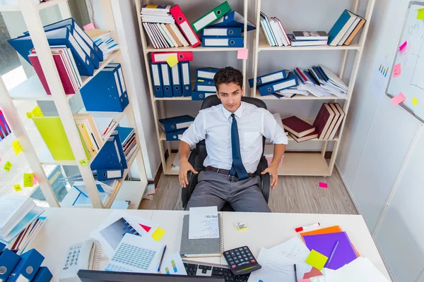 Empresario trabajando en la oficina con montones de libros y papeles —  Fotos de Stock