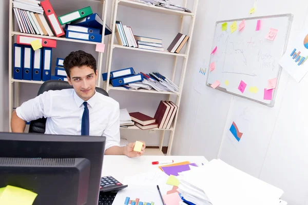 Ofiste kitap ve kağıtlarla çalışan bir işadamı.