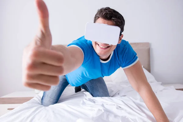 Jovem na cama vestindo um vr realidade virtual head set — Fotografia de Stock