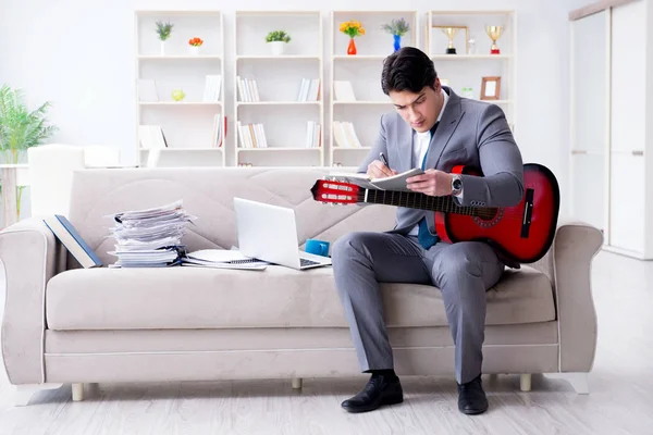 Evde gitar çalan bir iş adamı.