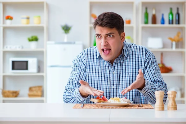 Genç koca öğle yemeğinde tatsız yemekler yiyor.