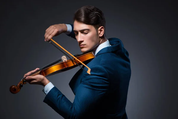 Junger Mann spielt Geige im dunklen Raum — Stockfoto