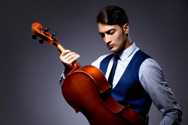 Jongeman die cello speelt in de donkere kamer — Stockfoto