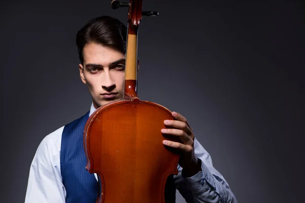 Jongeman die cello speelt in de donkere kamer — Stockfoto