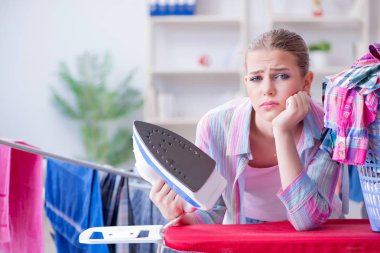 Üzücü kadın evde kıyafetleri ütülüyor.