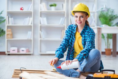 Tamirci kadın marangoz ahşap döşemeleri kesiyor.