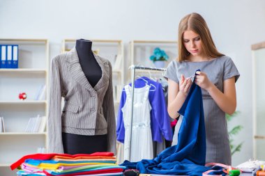 Atölyede çalışan genç bayan terzi yeni elbise üzerinde çalışıyor.