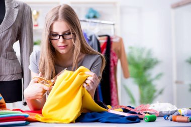 Atölyede çalışan genç bayan terzi yeni elbise üzerinde çalışıyor.