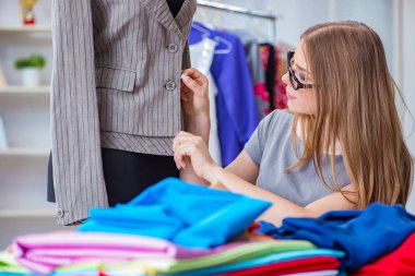 Atölyede çalışan genç bayan terzi yeni elbise üzerinde çalışıyor.