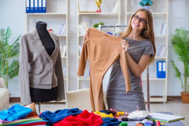 Atölyede çalışan genç bayan terzi yeni elbise üzerinde çalışıyor.