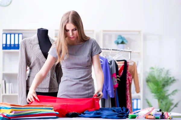 Mujer joven sastre trabajando en taller sobre vestido nuevo — Foto de Stock