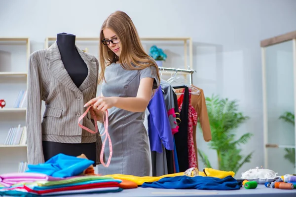 Atölyede çalışan genç bayan terzi yeni elbise üzerinde çalışıyor.