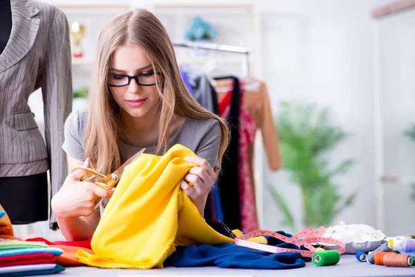 Atölyede çalışan genç bayan terzi yeni elbise üzerinde çalışıyor.