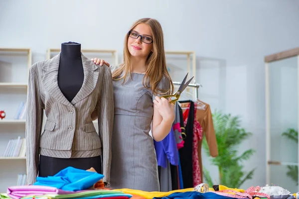 Atölyede çalışan genç bayan terzi yeni elbise üzerinde çalışıyor.