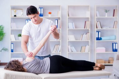 Genç doktor kayropraktik uzmanı kadın hastaya masaj yapıyor.