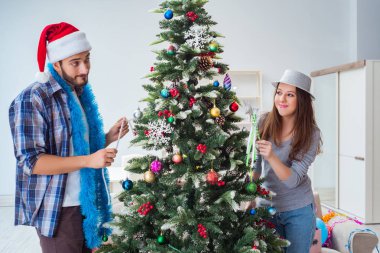Genç aile Noel ağacını mutlu bir vesileyle süslüyor.