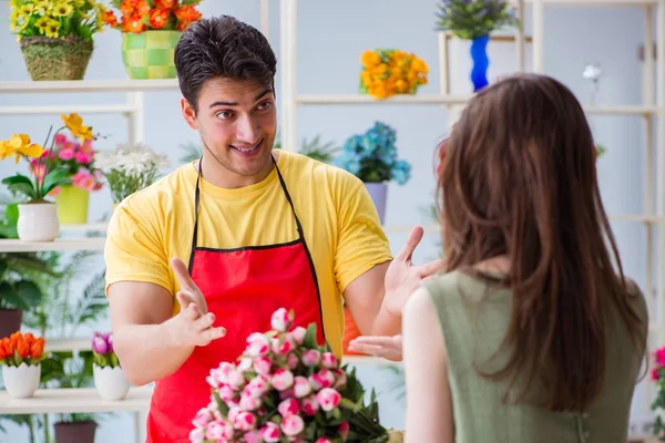 Çiçekçi dükkanında çiçek satıyor.