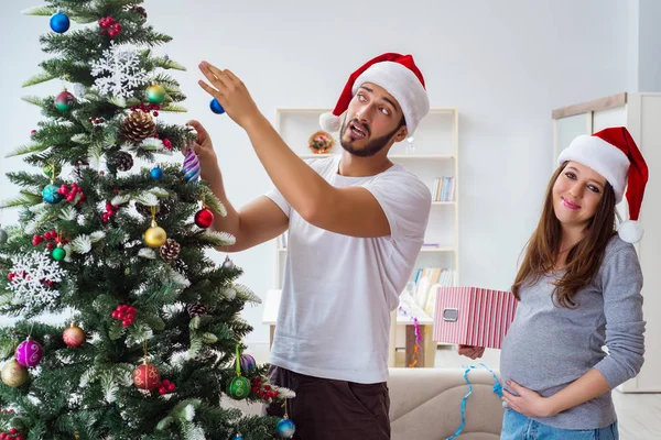 Молодая семья, ожидающая ребенка, празднующего Рождество — стоковое фото