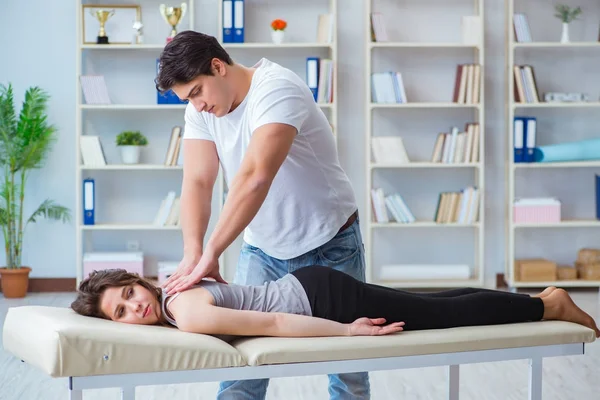 Genç doktor kayropraktik uzmanı kadın hastaya masaj yapıyor.