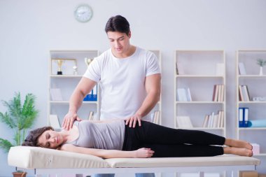 Genç doktor kayropraktik uzmanı kadın hastaya masaj yapıyor.